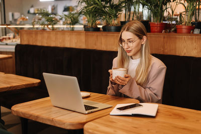 A business woman with glasses works online using a laptop. a student studies online sitting in cafe