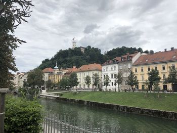 Buildings by canal against sky in city