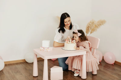 A young mother and her little daughter celebrate their birthday with a cake.