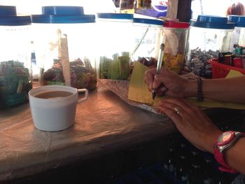 Midsection of woman holding drink on table