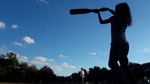 Low angle view of people playing against blue sky