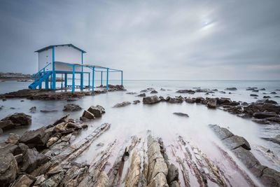 Lifeguard hut by sea against cloudy sky at dusk