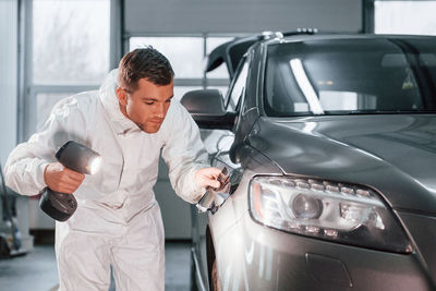 Using special equipment. man in uniform is working in the auto service.