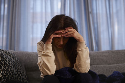 Woman sitting on sofa with headache