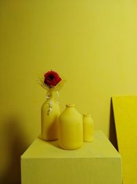 Close-up of yellow flower vase on table against wall