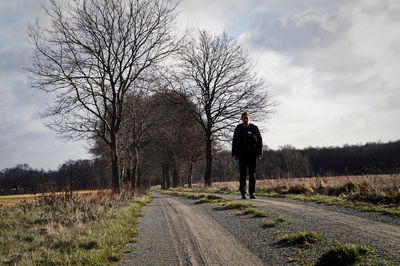 Man walking on footpath amidst field