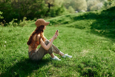 Side view of woman sitting on grassy field