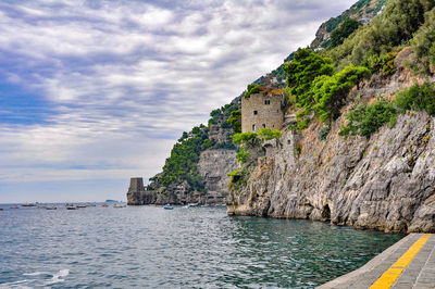 Scenic view of sea by cliff against sky