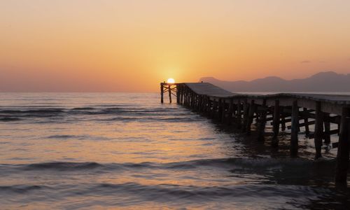 Pier on sea against sky during sunset