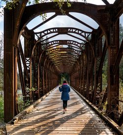 Rear view of woman walking on footbridge