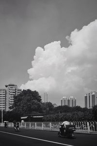 Cars on road by buildings against sky