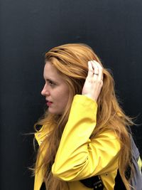 Beautiful woman with hand in hair standing against black background