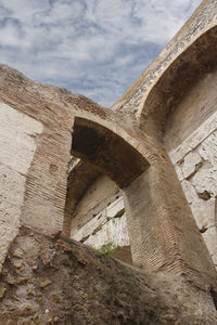 Low angle view of old ruin building against cloudy sky