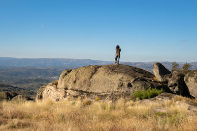 Woman standing on rock by mountain against sky