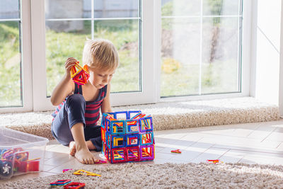 The child is playing with a multi-colored magnetic constructor, building a tower. educational toys 