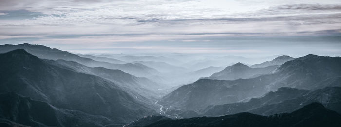 Scenic view of foggy mountains against sky