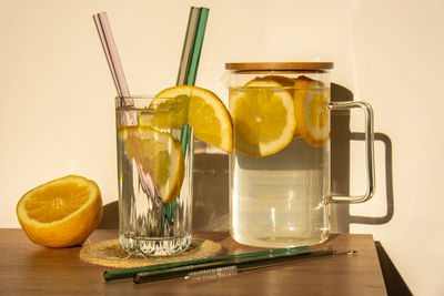 Glass of water with fresh lemon juice with reusable glass straws detox cold tonic water with sunny