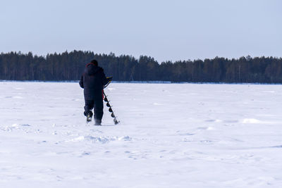 Full length rear view of man on snow covered land