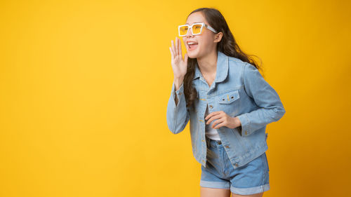 Young woman wearing mask against yellow background