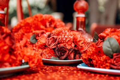 Red table wedding arrangement of roses, carnations on the background of a table with red tablecloth