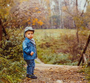 Full length of cute boy standing on street during autumn