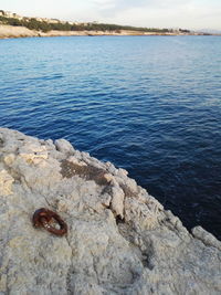 Close-up of rock by sea against sky