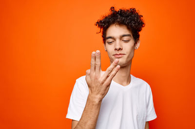 Portrait of teenage girl standing against orange background