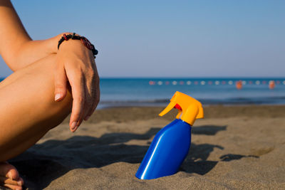 Midsection of woman on beach against sky