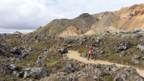 Young man hiking down the rocky trail in landmannalaugar