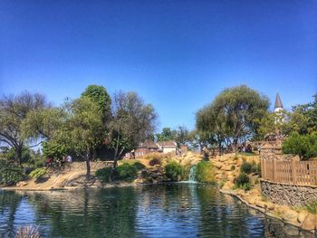 Swimming pool by river against clear blue sky