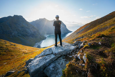 Rear view of man standing on rock against sky