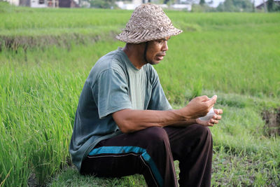 Side view of young man sitting on field