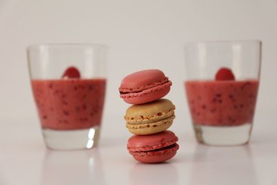 Close-up of macaroons and smoothie over white background