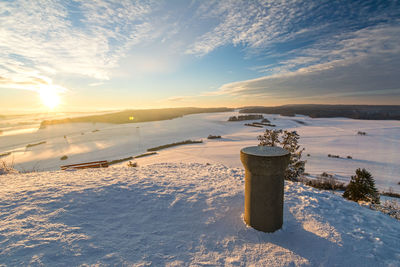 Scenic view of snow covered land against sky during sunset