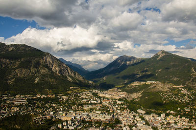 Scenic view of town by mountains against sky