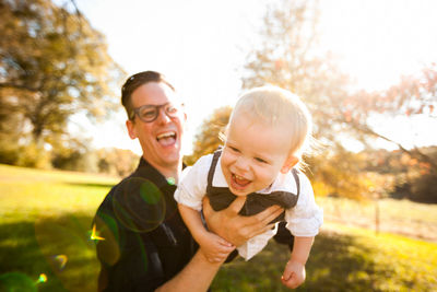 Portrait of happy father and daughter in park against sky