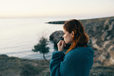 Young woman standing by sea against sky