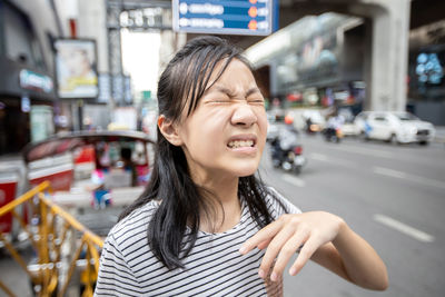 Portrait of smiling young woman on road in city