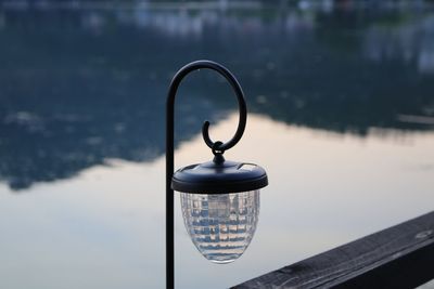 Close-up of electric lamp hanging by lake against sky