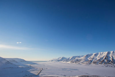 Scenic view of snowcapped mountains against clear blue sky
