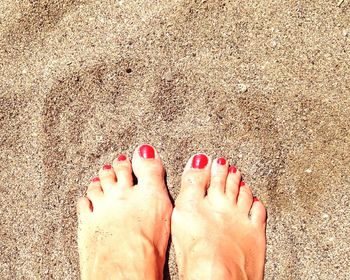 Low section of woman standing on sand