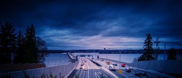 High angle view of vehicles on bridge over river against sky at dusk
