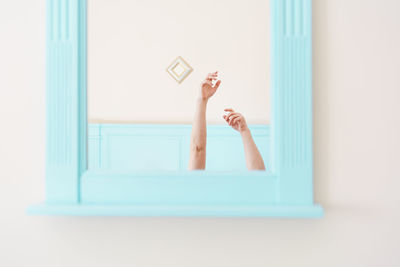 Man with arms raised against mirror and wall at home