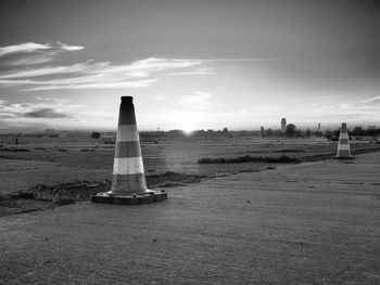 Traffic cones on road against sky during sunset