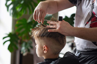 Barbershop and hairdressing at home. men's and children's haircuts. the hairdresser cuts the boy. 