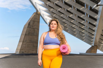 Young woman standing with yoga mat