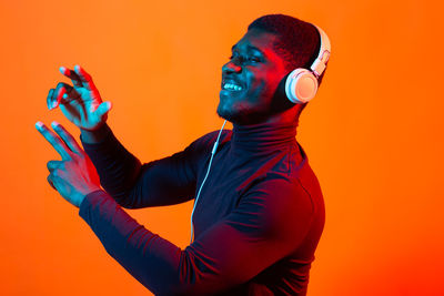 Side view of man wearing mask against orange background