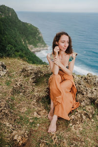 Portrait of beautiful young woman on cliffs edge near ocean.