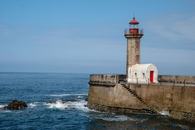 Lighthouse by sea against sky