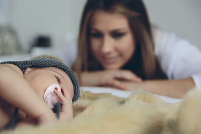 Mother looking at sleeping daughter on bed at home